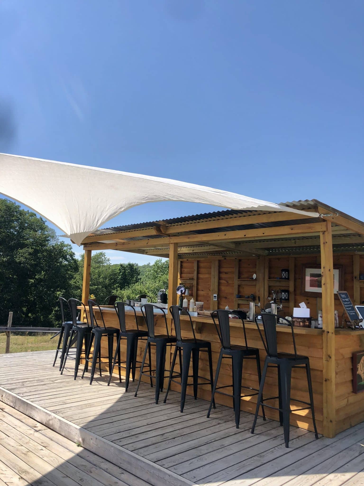 The Rooting Pig, Broad Arrow Farm's Charcuterie Bar.  Picture of the outdoor bar with bar stools and bright blue sky