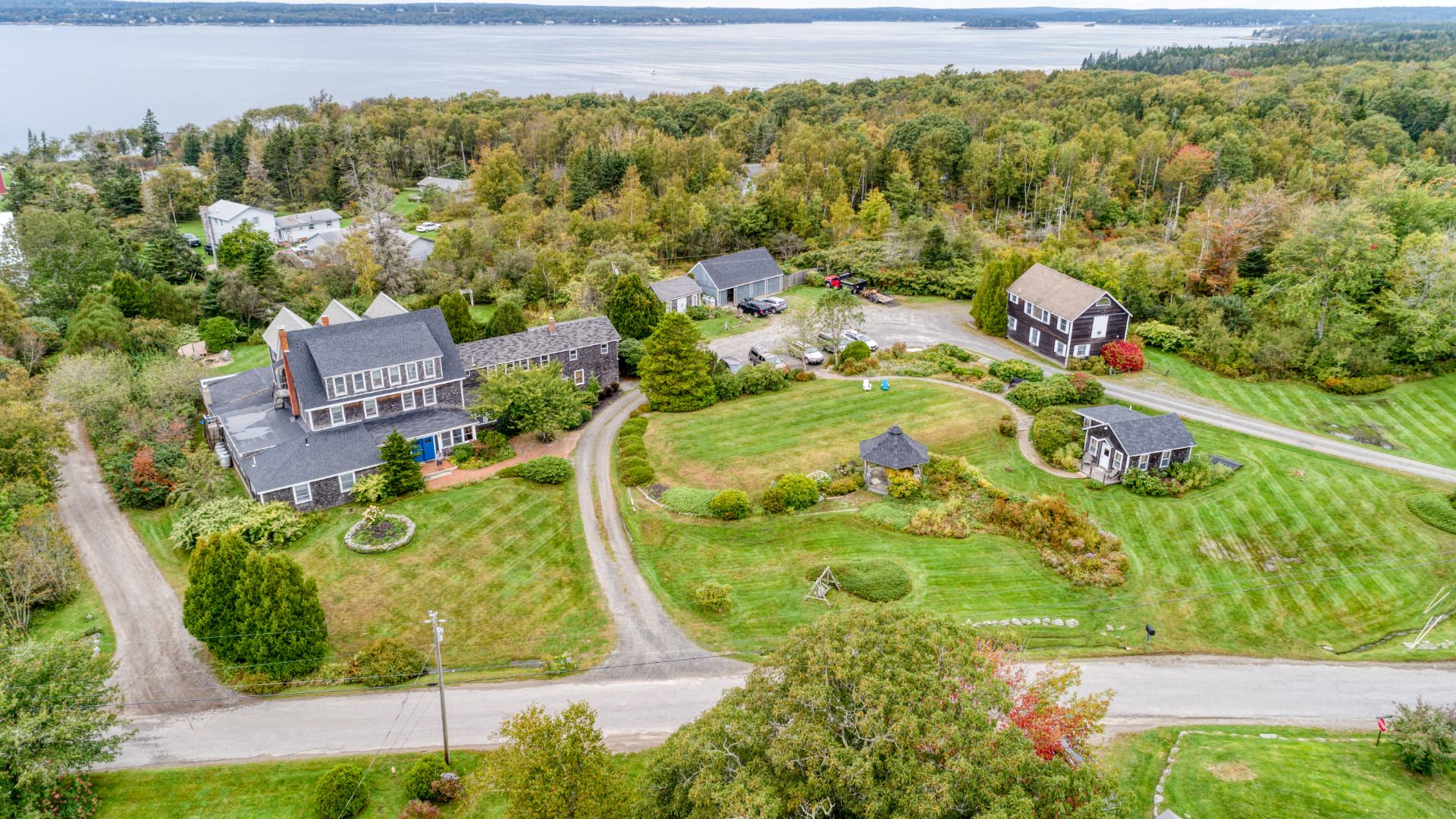 Exterior aerial view of property surrounded by green grass, bushes and trees