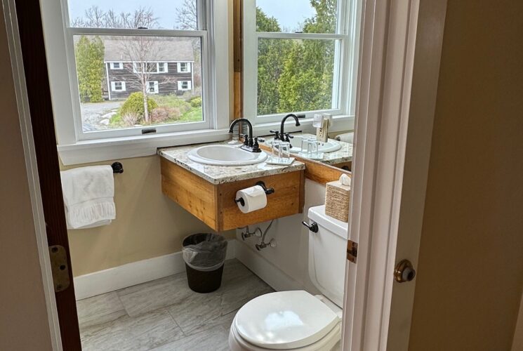 View into the bathroom with beautiful tile floor, sink with granite countertop, large mirror and bright vanity lamp. Bathroom also has a nice large window.
