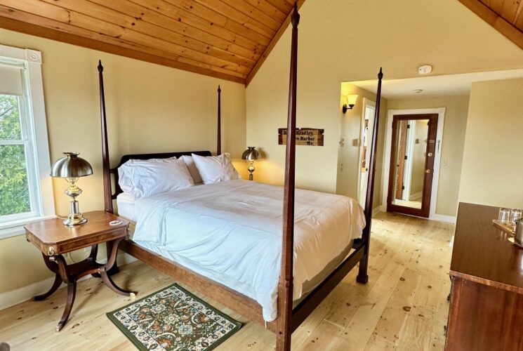 View of the room towards the entry. Beautiful natural colored pine floors, golden ship lap high ceiling, high four posted bed.