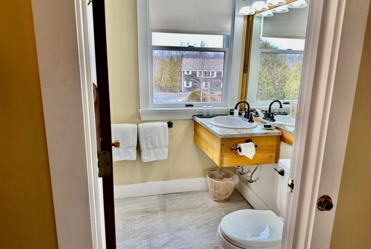 Looking into the bathroom, with it beautifully tiled floor, new toile, fluffy towels and oil rubbed accents with a view out the window.
