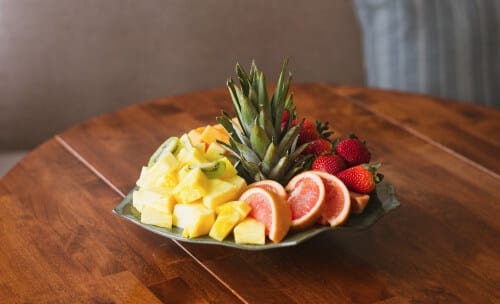 A big plate of fruit which includes pineapple, strawberries, grapefruit and banana