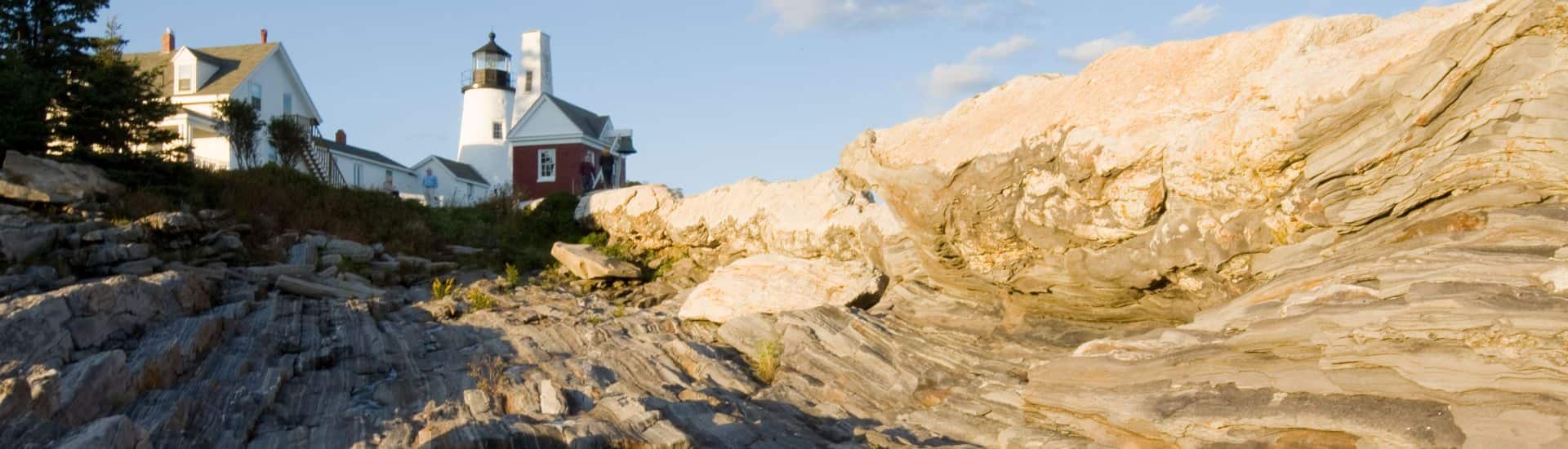 Lighthouse on a hill surrounded by large rock formations