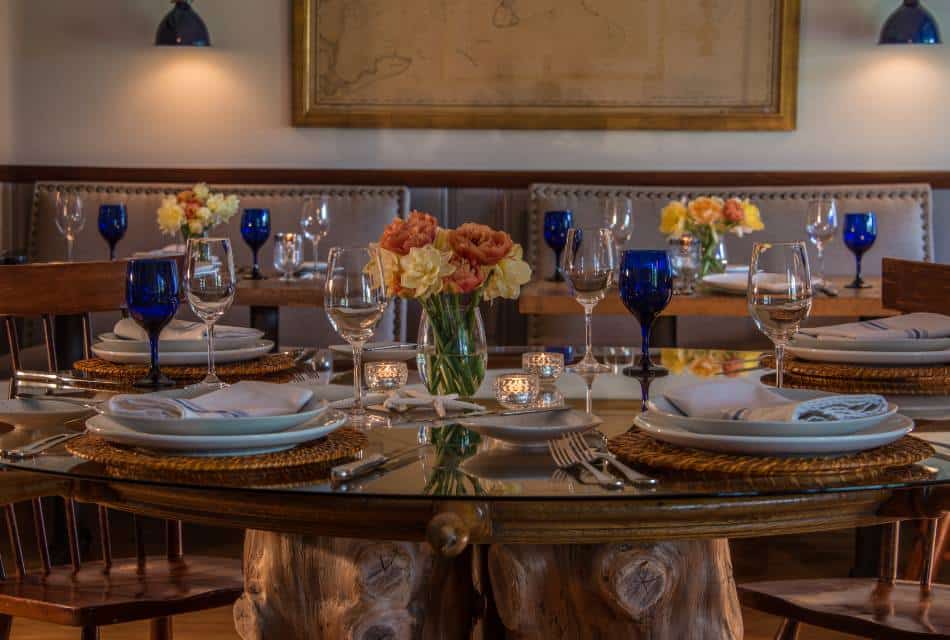 Dining room with wooden tables, wooden chairs, upholstered benches, and placesettings