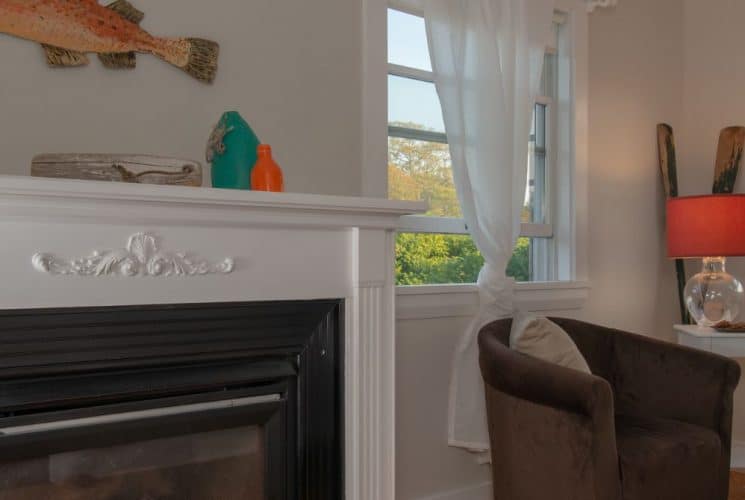 Large bedroom suite with white walls, hardwood flooring, fireplace, and sitting area