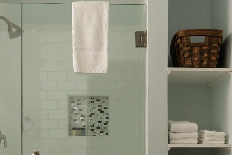 Bathroom with light-colored walls, tiled stand-up shower, and storage shelves