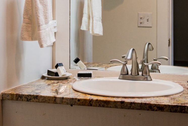 Bathroom with white walls, quartz vanity top, white sink, and large mirror