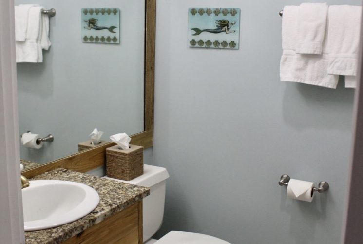 Bathroom with light blue walls, quartz vanity top, white sink, and large wooden framed mirror