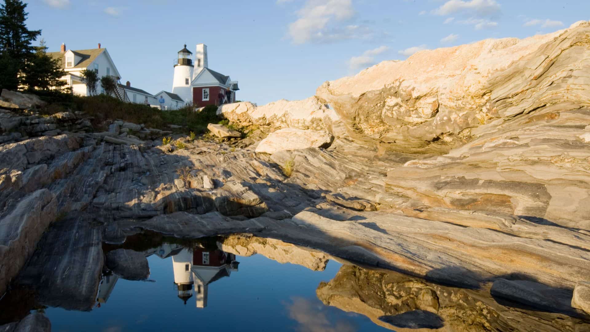 Lighthouse on a hill surrounded by large rock formations