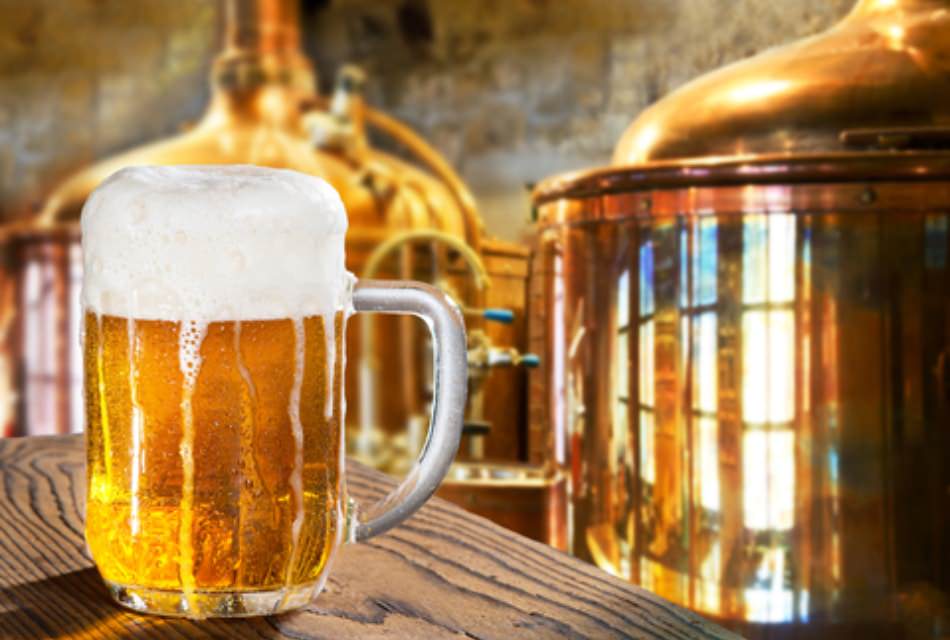 Close up view of a mug of beer with distilleries in the background