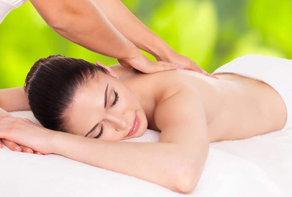 Close up view of woman laying on white table covered in white towel getting a massage