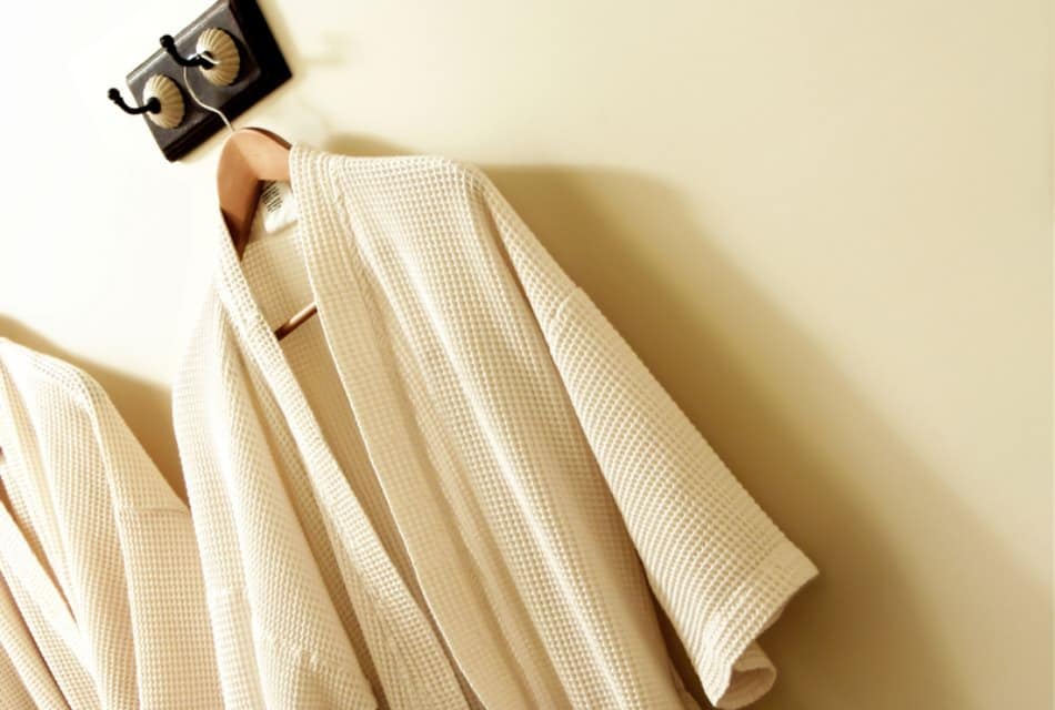 Close up view of two cream robes hanging on wall hooks