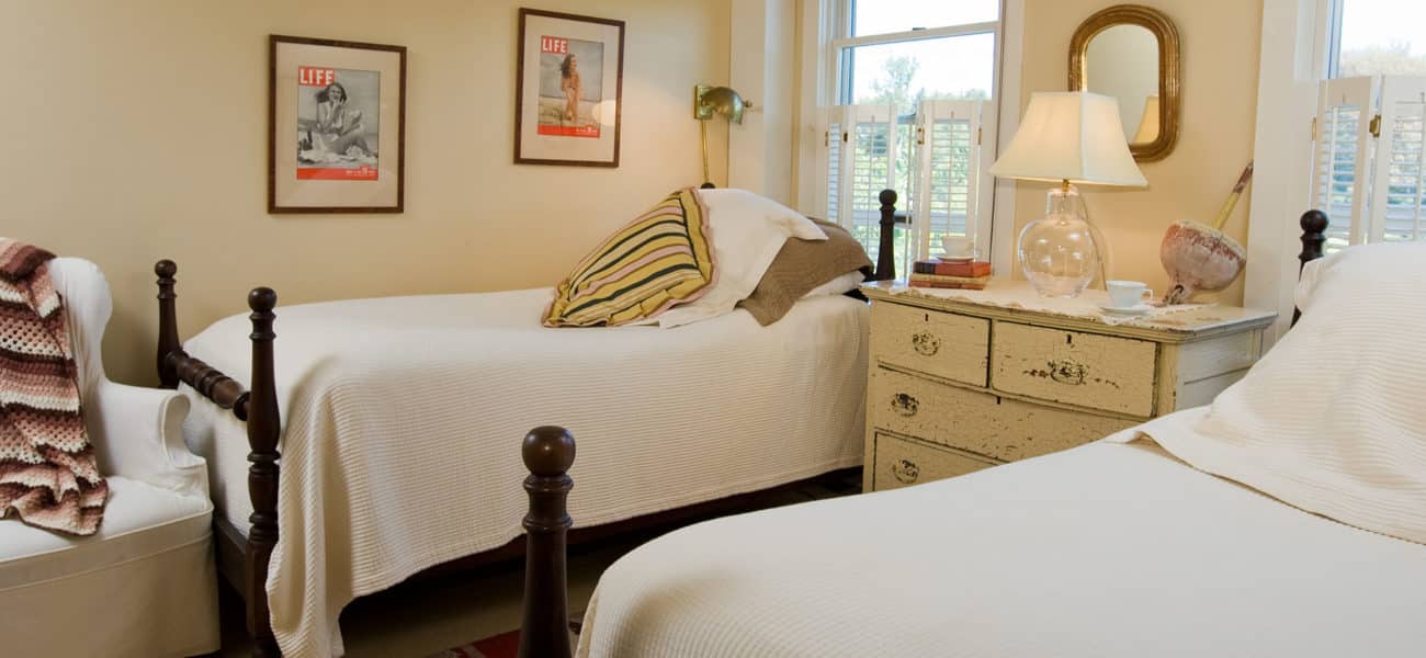 two twin size beds with white devuts and gold throw pillows with a dresser in between.