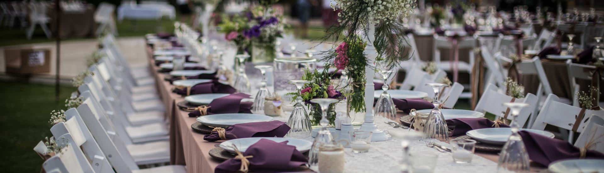 Long rows of tables, chairs, and placesettings all set up for a large event